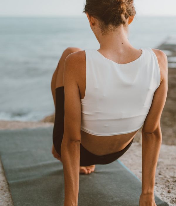 Person stretching gently on a yoga mat at sunrise.